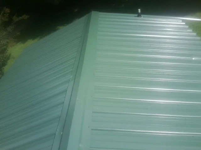 New green metal panels meeting at the ridge of a roof — Flat Roof Repair work by our crew in Wrightsville