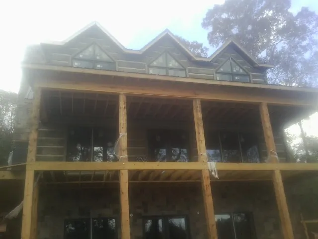 Dormers and porch framing on a large log home under construction — Roof Coating work by our crew in Wrightsville