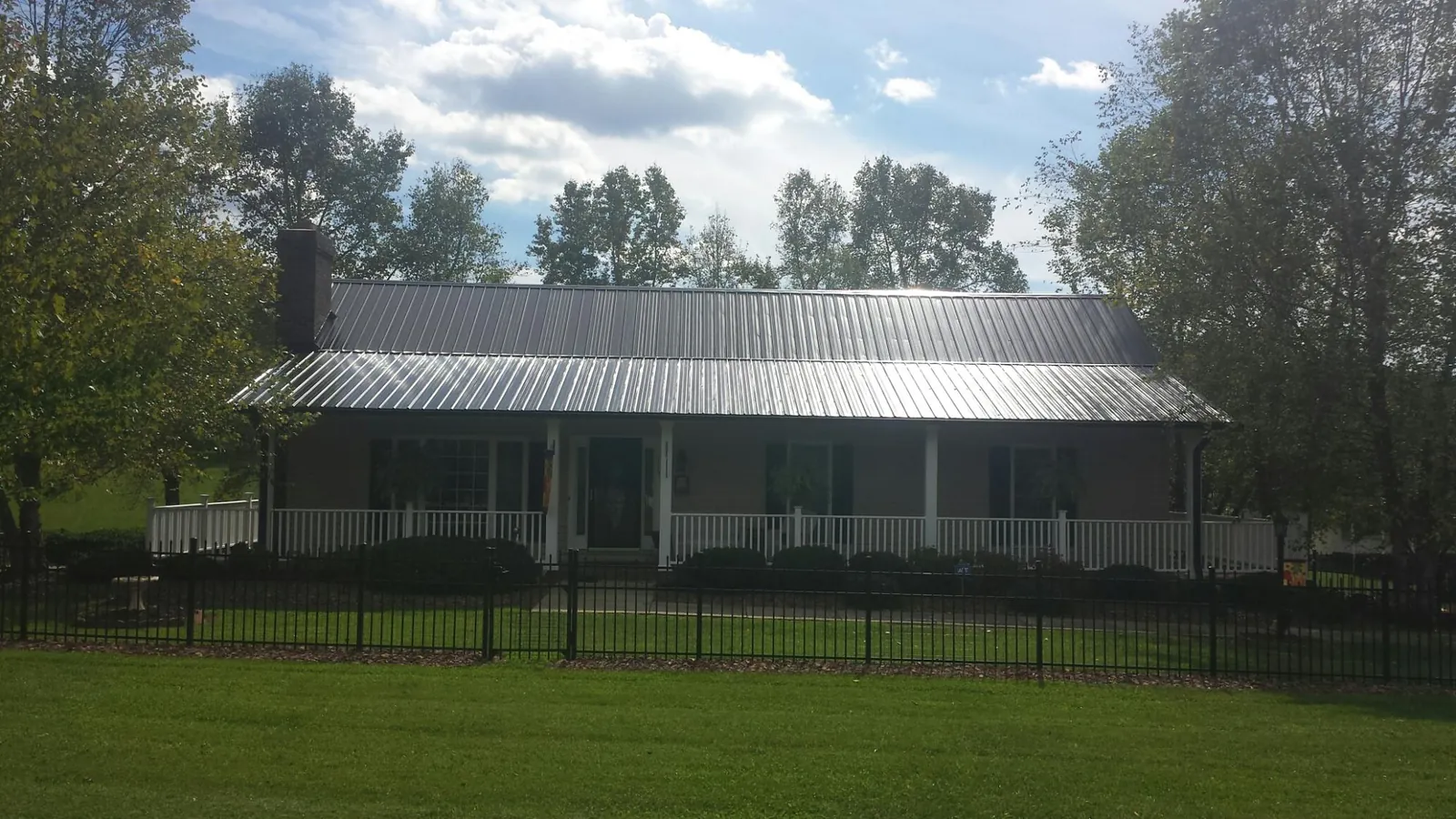 Gray metal roof on a brick ranch with a full width front porch — Gutter Guard Installation work by our crew in Wrightsville