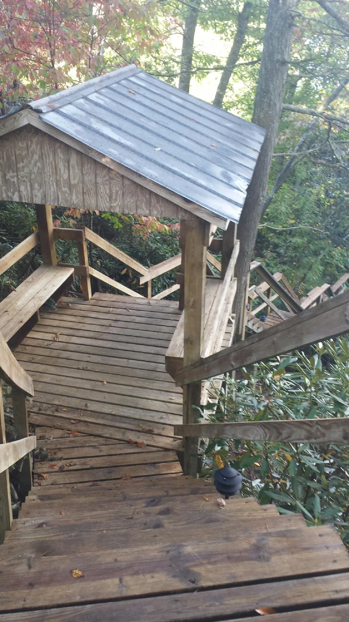 Metal roofed shelter over wooden steps on a wooded walkway — Skylight Repair & Installation work by our crew in Wrightsville