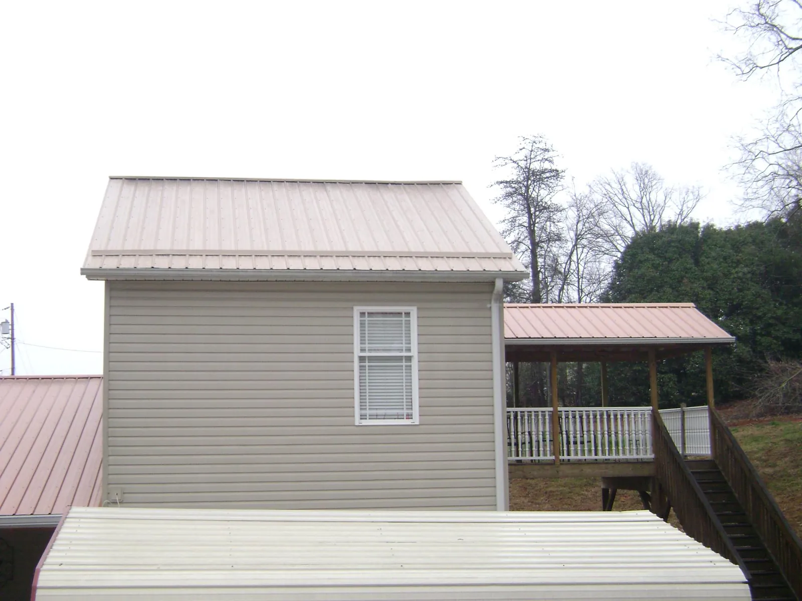 Tan metal roofs on a two story addition and attached porch, from a Roof Replacement job in Wrightsville