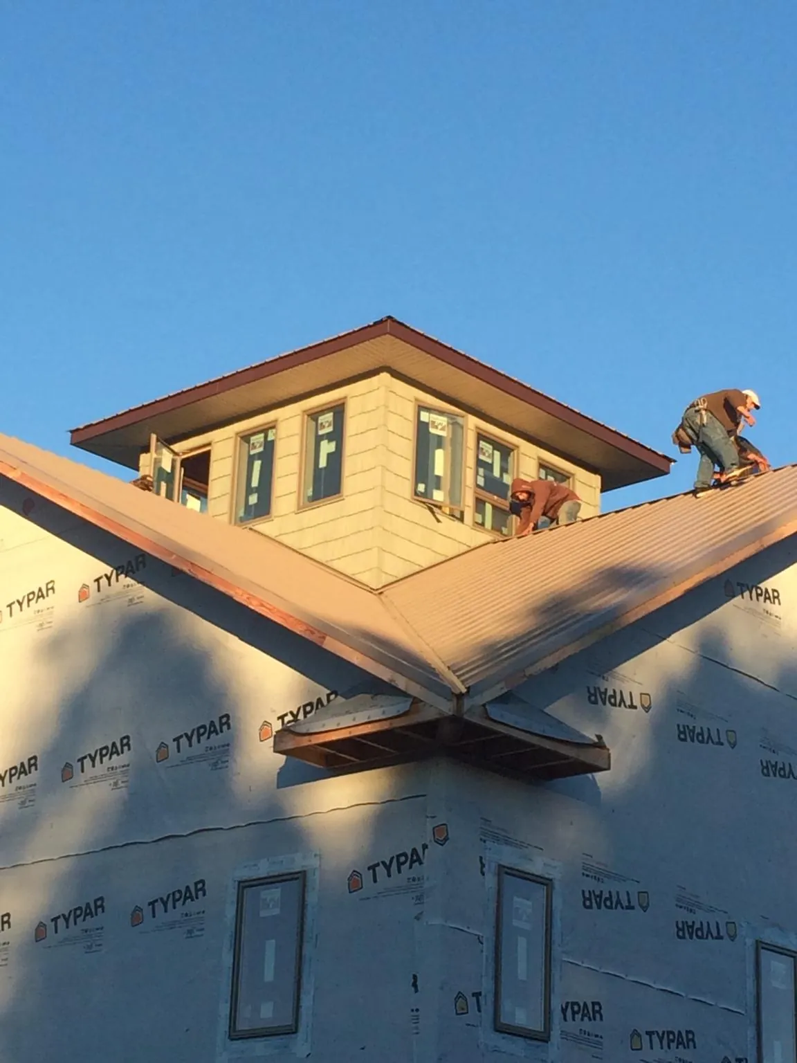 Roofers working around a rooftop cupola on a new metal roof at sunset — Roof Waterproofing in Wrightsville by Roofing Brothers
